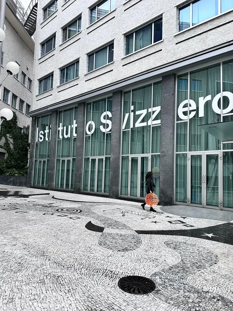 Une personne qui passe devant un bâtiment avec une signalétique sur celui-ci